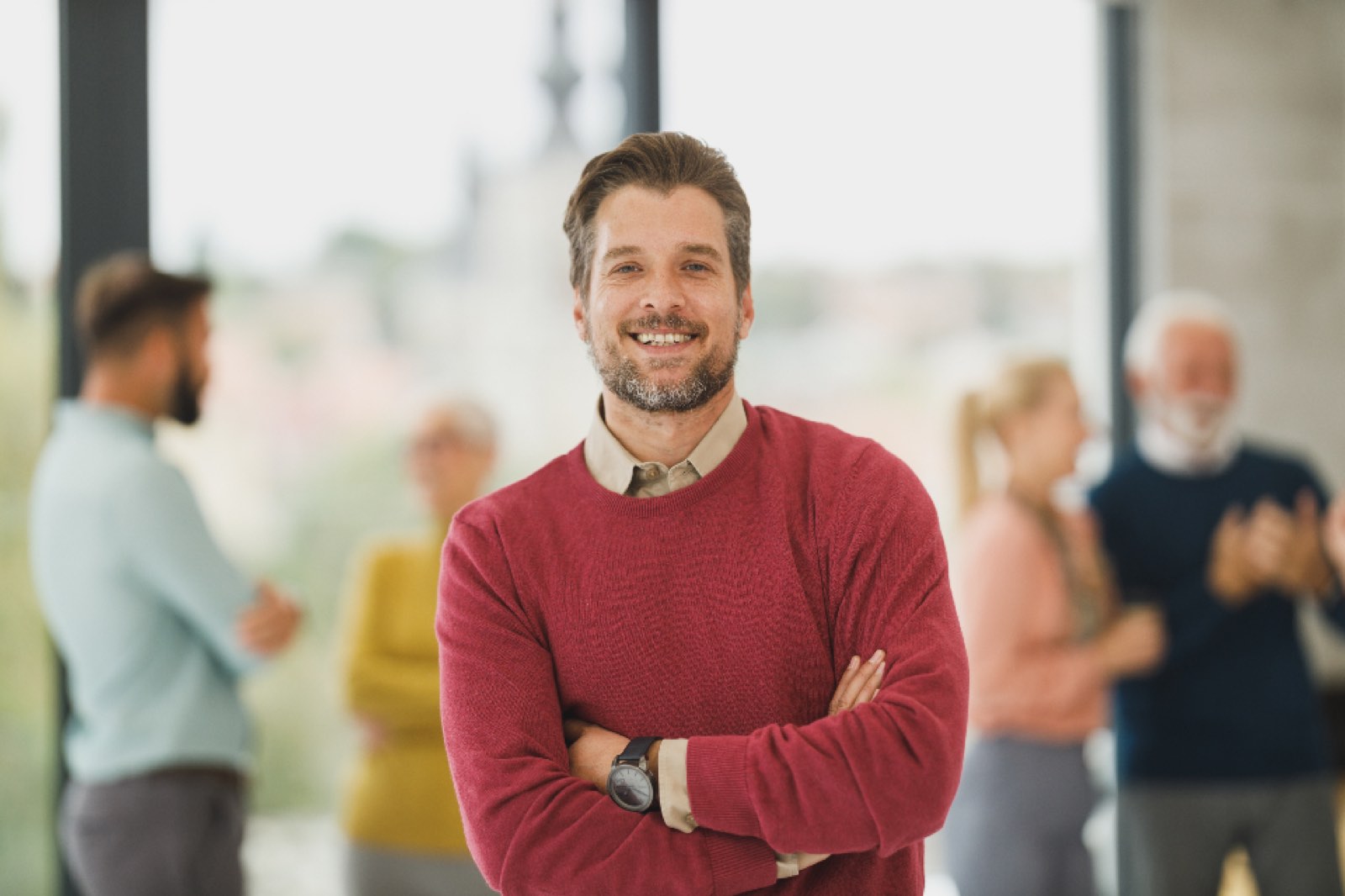A smiling man with colleagues behind him