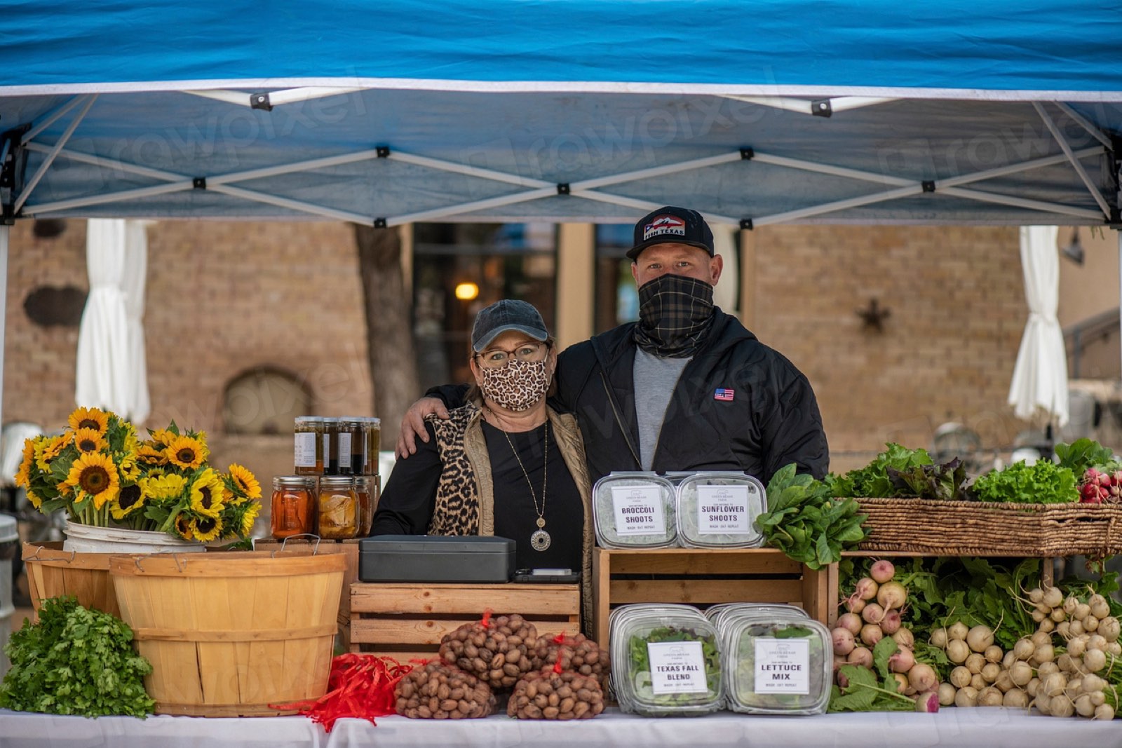 Vendors at a market stall with flowers and produce
