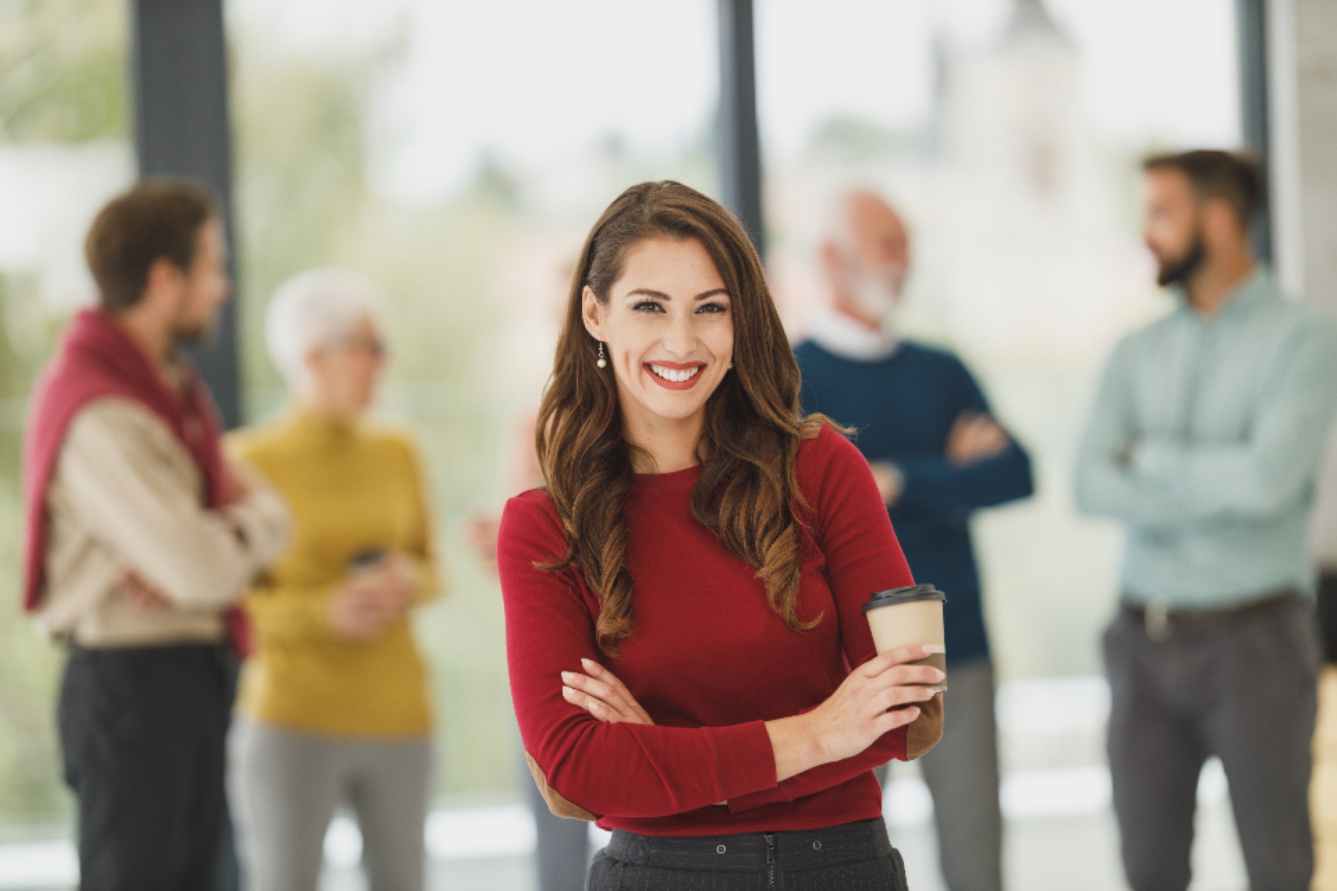 A smiling woman in an office with her team behind her