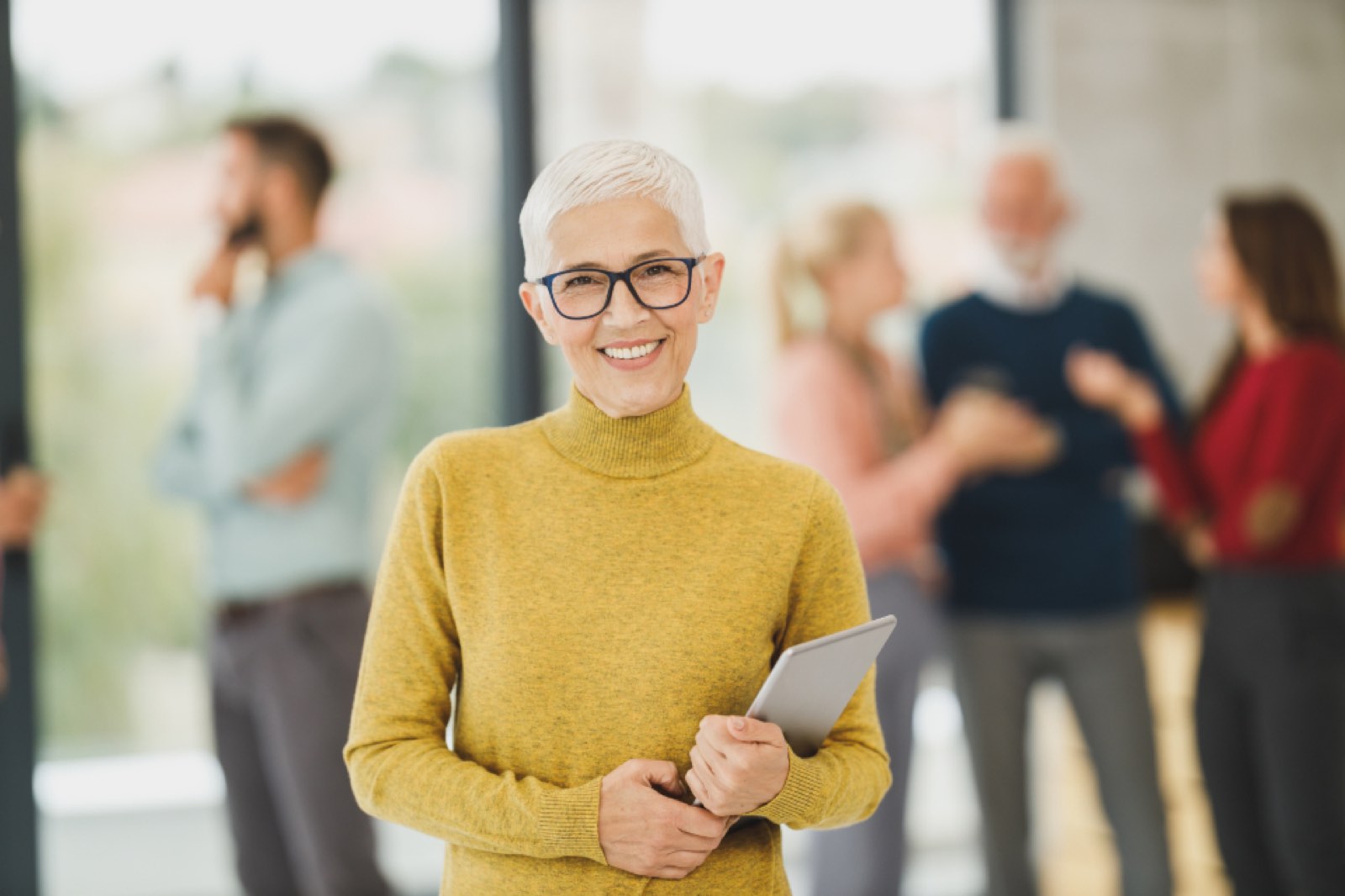 A smiling woman in a yellow sweater at work